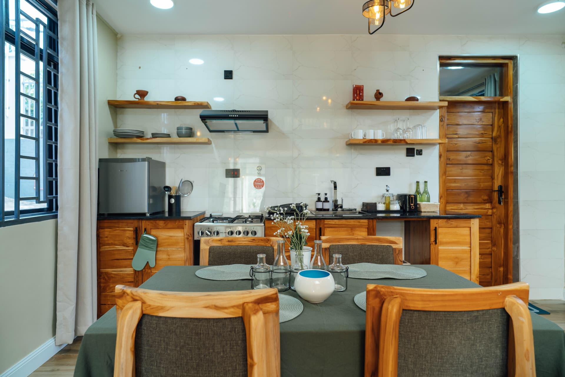 Fully equipped kitchen with open wood shelving in a Starico Residence apartment